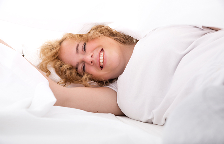 Woman lying sideways on a bed smiling